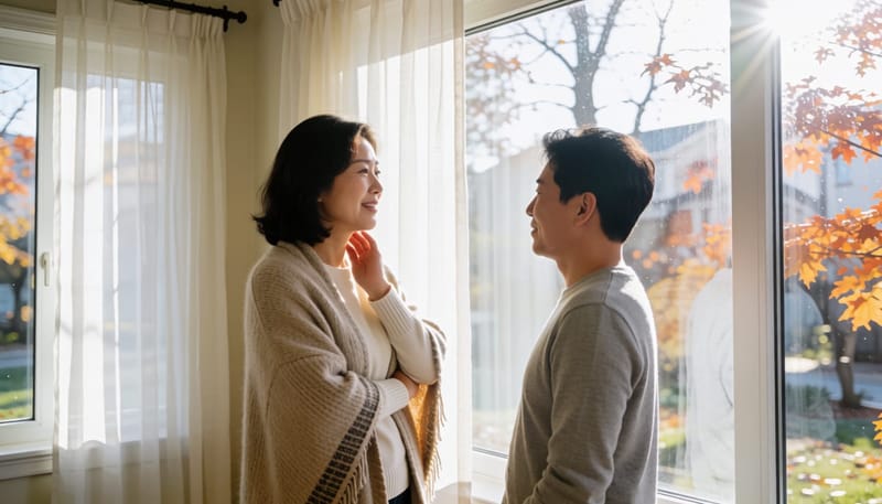 환절기 아침, 건조한 목을 만지며 창가에 서 있는 여성