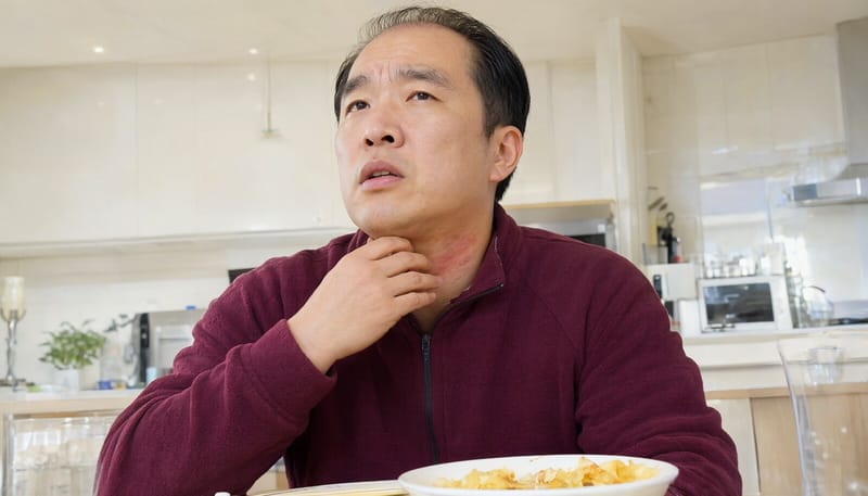 음식을 먹은 뒤 목과 피부에 두드러기가 올라와 걱정스러워하는 남성
